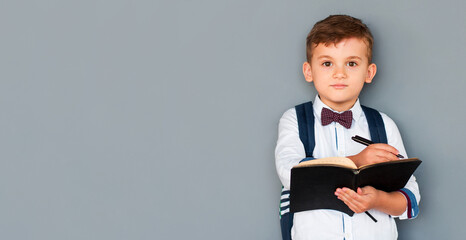 Portrait of cute healthy happy school kid boy making homework. Little child writing with a pen, indoors. Elementary school and education. Kid learning writing letters and numbers