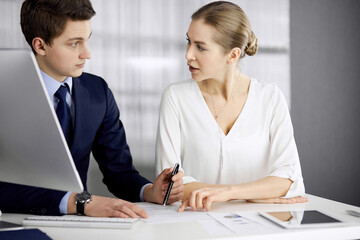 Obraz premium Business people discussing something while sitting in office. Focus at businesswoman while talking to her male colleague. Teamwork and meeting concept