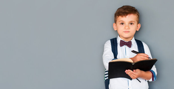 Portrait of cute healthy happy school kid boy making homework. Little child writing with a pen, indoors. Elementary school and education. Kid learning writing letters and numbers