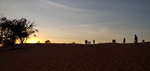 Fototapeta na wymiar the desert of Vietnam. silhouette of sand mountains and sunset people