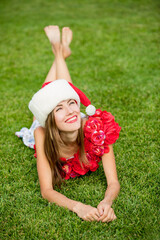 Beautiful santa claus woman over green resort background. Winter holiday in summer scenery concept