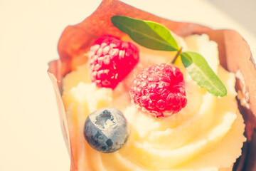 Cheesecake with bright sweet berries of raspberries and blueberries. Cheesecake wrapped in an eco-friendly wrapper of yellow paper paper.