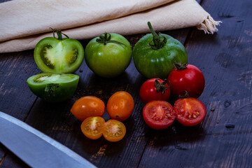 still life with fresh red, green and yellow tomatoes freshly picked from the garden on the wooden table and knife