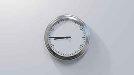 Glossy chrome clock on a white wall at quarter to nine. Time is 08:45 or 20:45