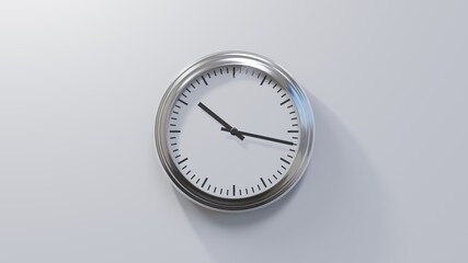 Glossy chrome clock on a white wall at seventeen past ten. Time is 10:17 or 22:17