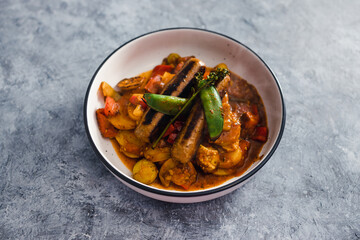 plant-based food, tomato potato and snowpeas roast with vegan sausages