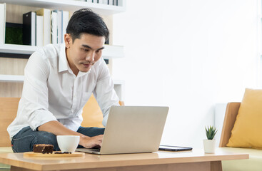 Fototapeta premium young handsome asian man using computer to work from home. business and technology concept
