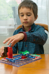 The boy playing an electric constructor. The child is played by intellectual toys. A boy in a blue shirt masters electronics. The concept of early development of children. vertical photo