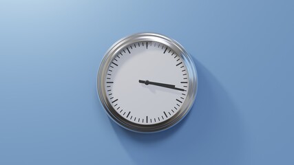 Glossy chrome clock on a blue wall at seventeen past three. Time is 03:17 or 15:17