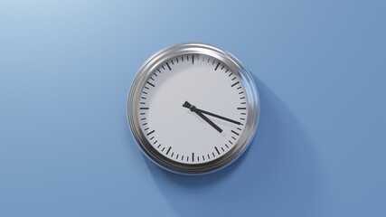 Glossy chrome clock on a blue wall at eighteen past four. Time is 04:18 or 16:18