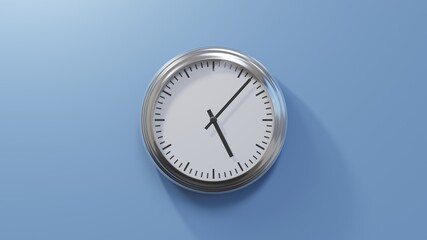 Glossy chrome clock on a blue wall at seven past five. Time is 05:07 or 17:07