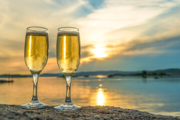 Two glasses with champagne on the background of the sunset, in nature, outdoors. Ramontic evening for lovers