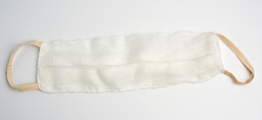 Obraz premium reusable mask of white cotton gauze on a white background, homemade remedy for viral diseases