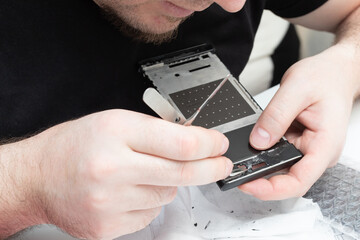 Replacing faulty modules in a mobile phone. The master removes fragments of the smartphone screen