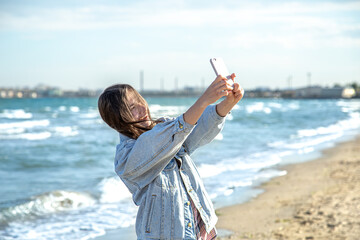 A young woman takes a selfie photo by the sea