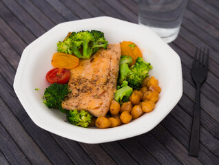 appetizing cooked trout, chickpeas, broccoli in white vintage bowl