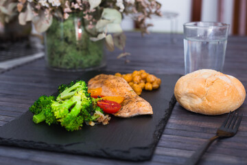appetizing cooked trout, chickpeas, broccoli on a black warm stone plate