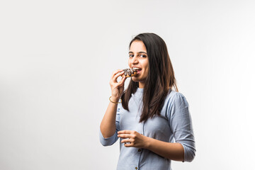 Indian girl eating chocolate donut, Isolated over white background