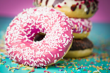 Multicolored sweet donuts with decoration on colourful background.