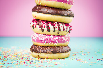Multicolored sweet donuts with decoration on colourful background.