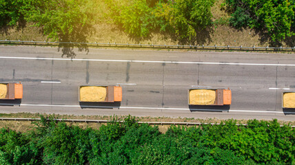 Aerial. Sand trucks driving on the highway. Delivery of building materials to the object. Top view...