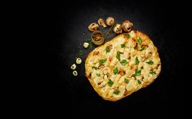 Delicious freshly baked square pizza with melted cheese and mushrooms on black background with ingredients, top view