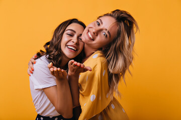 Winsome white girls posing in studio with smile. Lovable caucasian female friends relaxing during...