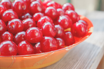 Bright sweet cherry berries in a plate. Vitamin gifts of a warm summer. Healthy natural delicacy.