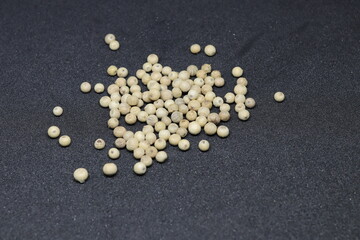 Fototapeta na wymiar White pepper grains isolated on black background