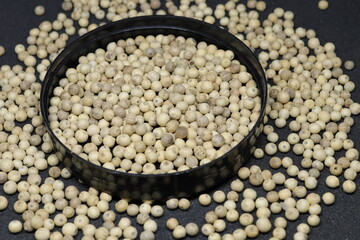 White pepper grains isolated on black background