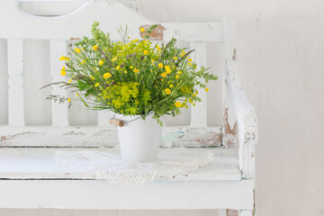 flowers in bucket on old white wooden bench indoor