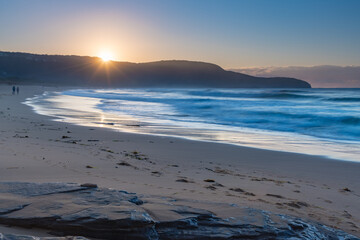 Clear skies winter sunrise seascape with sunburst over the headland