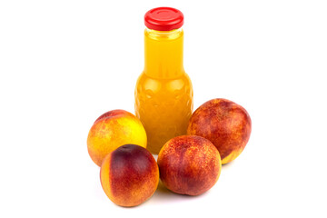 A bottle of nectarine juice. Nearby are juicy, beautiful nectarines.