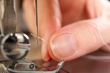 Obraz na płótnie Canvas woman threading a needle on a sewing machine. close up, selective focus.