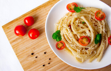 Spaghetti with cherry tomatoes and cheese on a wood board