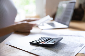 Crop close up of calculator machine or financial documents lying on table, woman manage household...