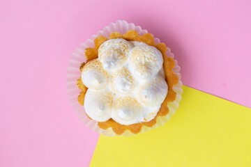 Top view of sweet cakes, white cream on a pink and yellow background. There space for text and mock up