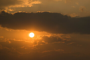 The sun receding beyond the horizon and dark clouds above it (option 2)