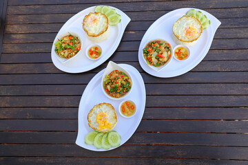 Pad Ka-prao; stir fried chopped chicken with chili and basil, served with steamed rice and fried egg on top set on wooden table