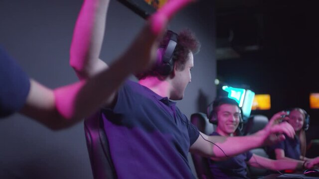 Cybersport team consisting of three young men and one woman winning round of shooter game and doing high five
