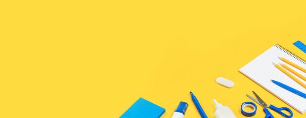 Assorted office and school white and blue stationery on bright yellow background. Organized...