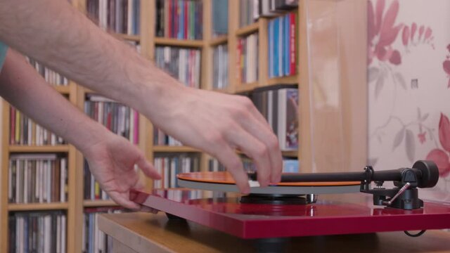  Putting an orange vinyl lp on a record player and playing it midshot