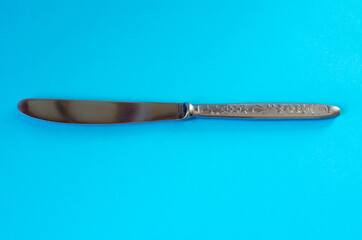Metal knife for butter on a blue background. Special unsharpened knife.