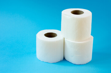 Three rolls of white toilet paper on a blue background