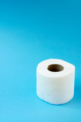 Roll of white toilet paper on a blue background vertical photo. Personal hygiene products.
