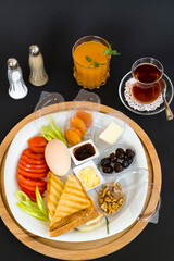 Traditional Turkish Breakfast Plate with boiled egg,orange juice and tea on black surface.Top view