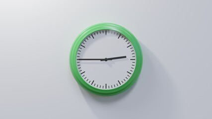 Glossy green clock on a white wall at quarter to three. Time is 02:45 or 14:45