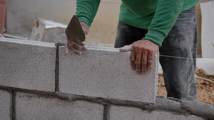 close up at the bricklayer  hands, the builder puts the bricks at construction site