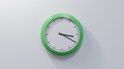 Glossy green clock on a white wall at twenty past three. Time is 03:20 or 15:20