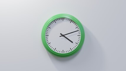 Glossy green clock on a white wall at twelve past four. Time is 04:12 or 16:12